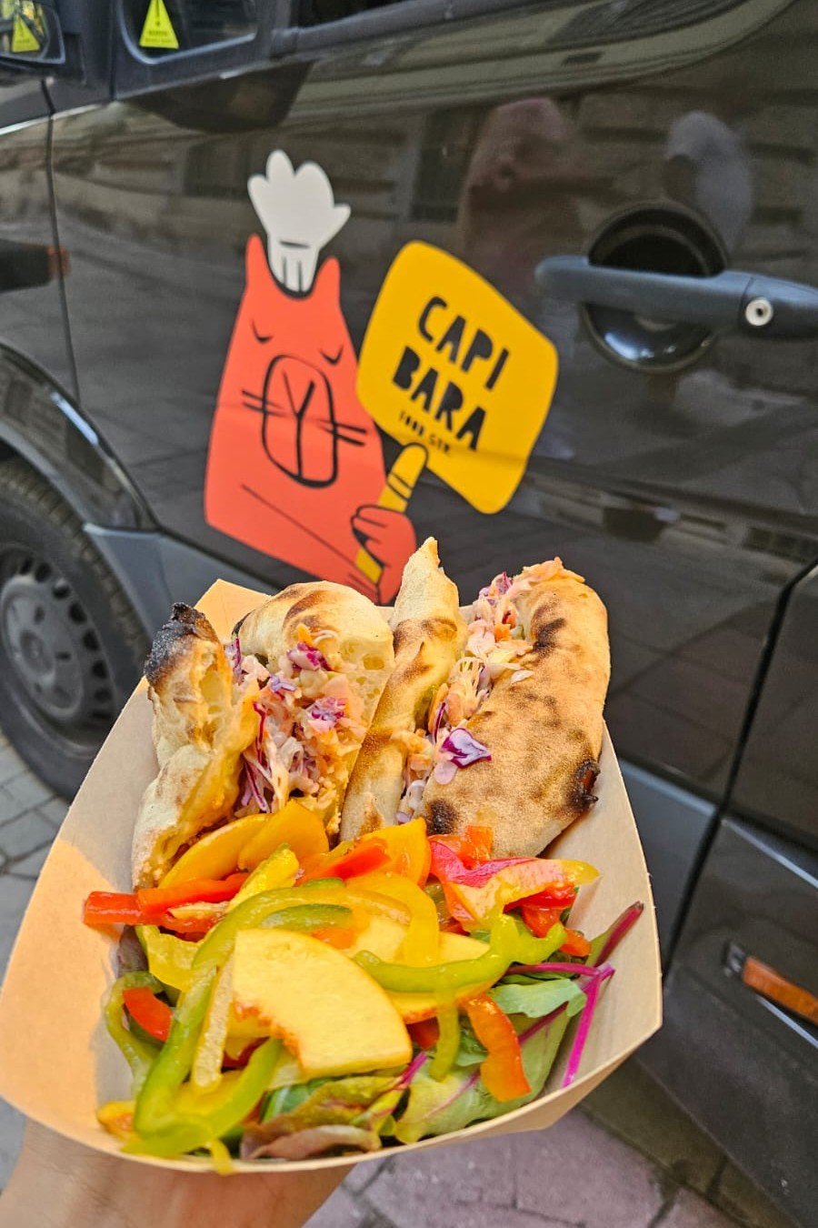 Sandos in front of the Capibara logo on truck door